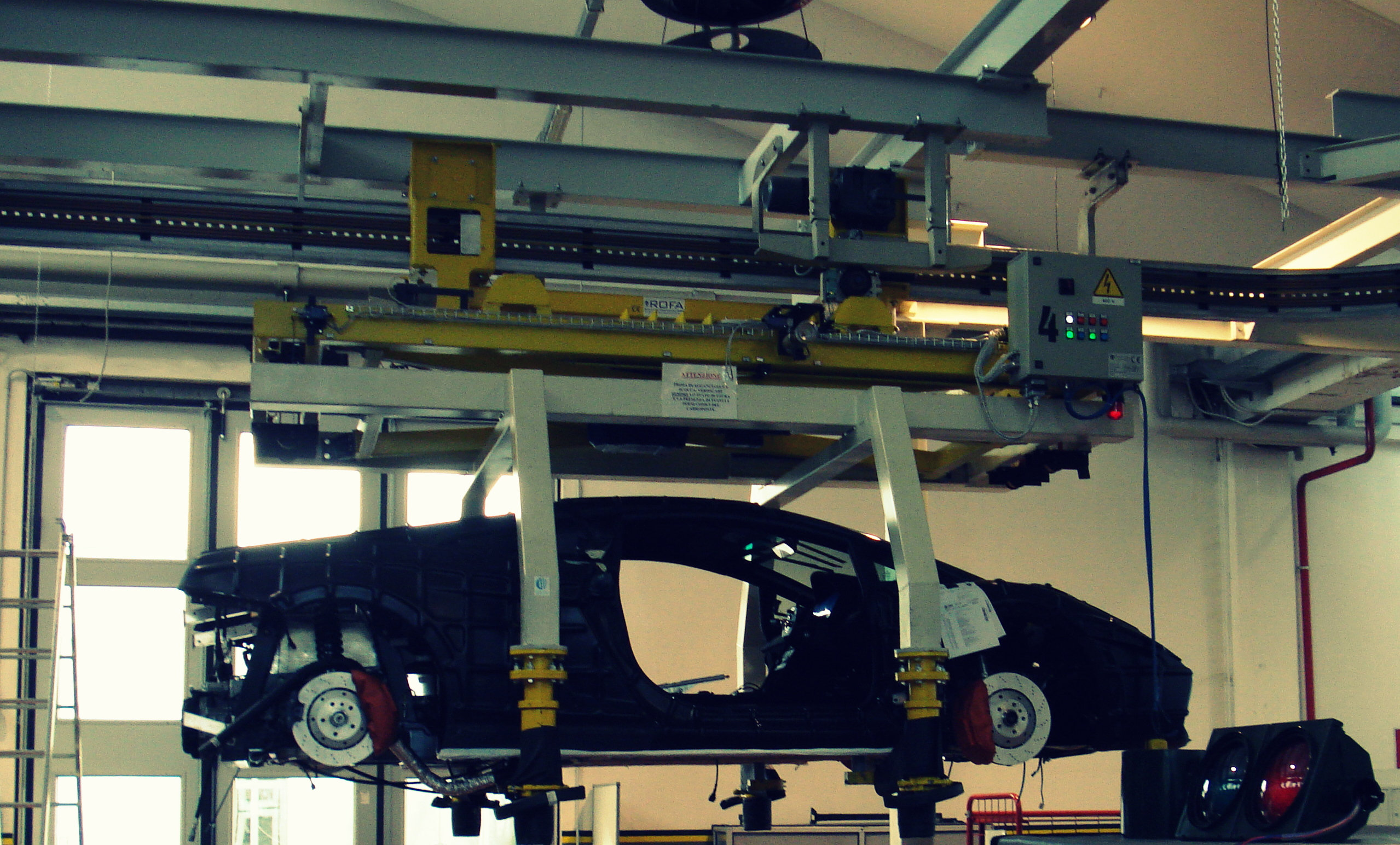 Carrozzeria di Lamborghini nera sospesa a un sistema di sollevamento aereo con binario e quadro di controllo ROFA.