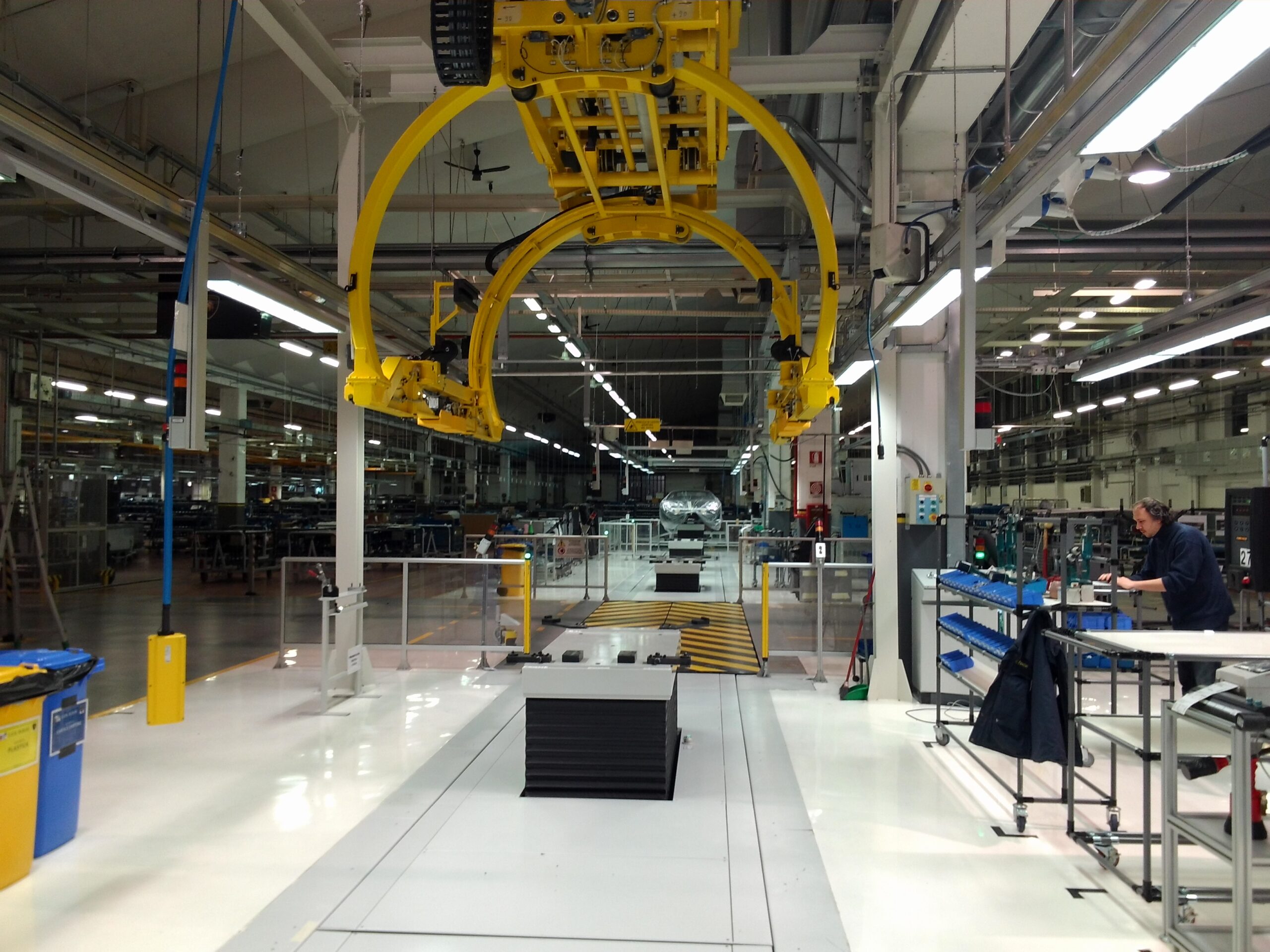 Struttura di movimentazione sospesa gialla per scocche auto, installata su rotaie aeree con sistemi di comando elettrico.