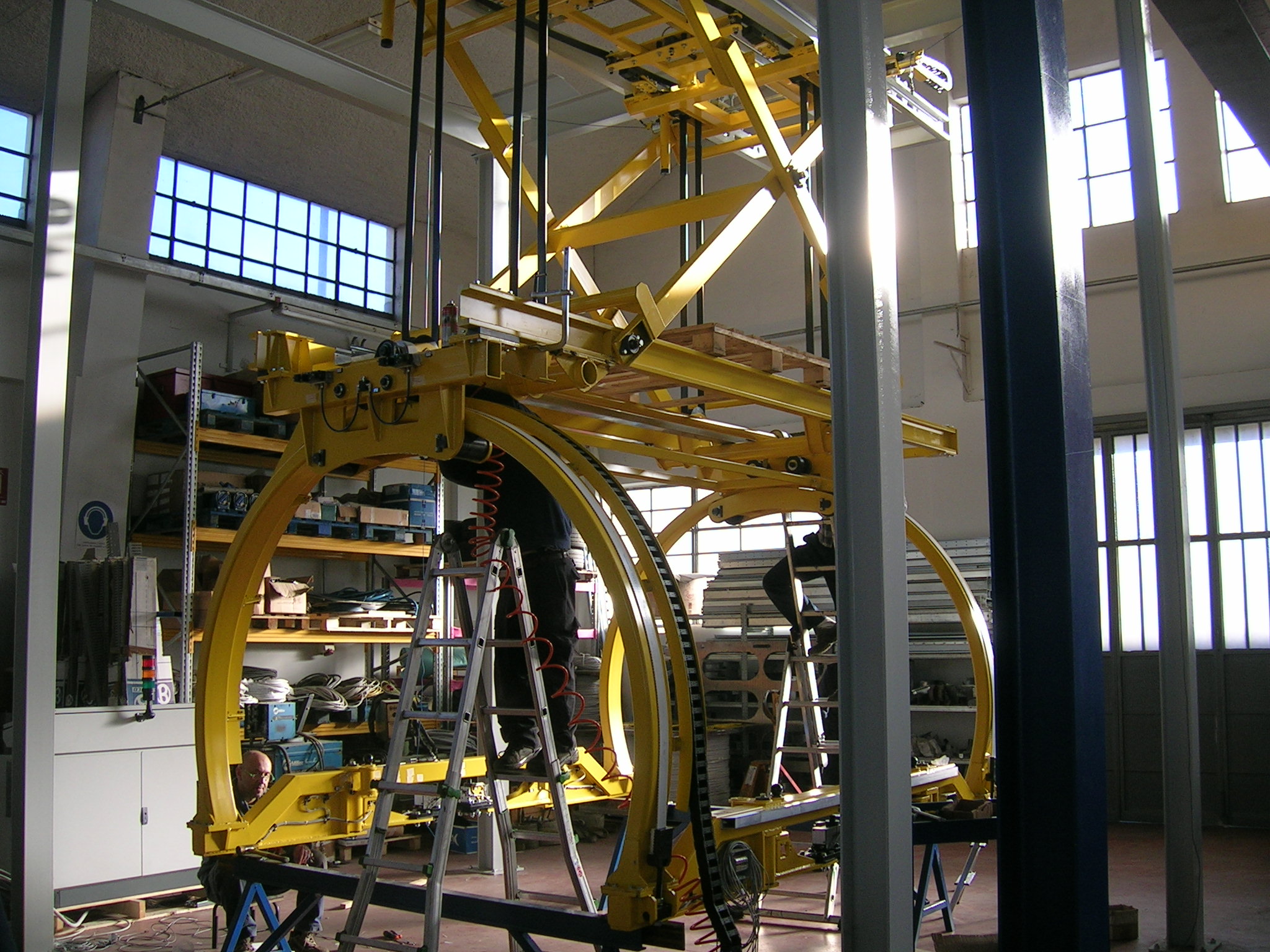 Struttura gialla ad arco per movimentazione scocche in fase di assemblaggio, posizionata in un’officina industriale.