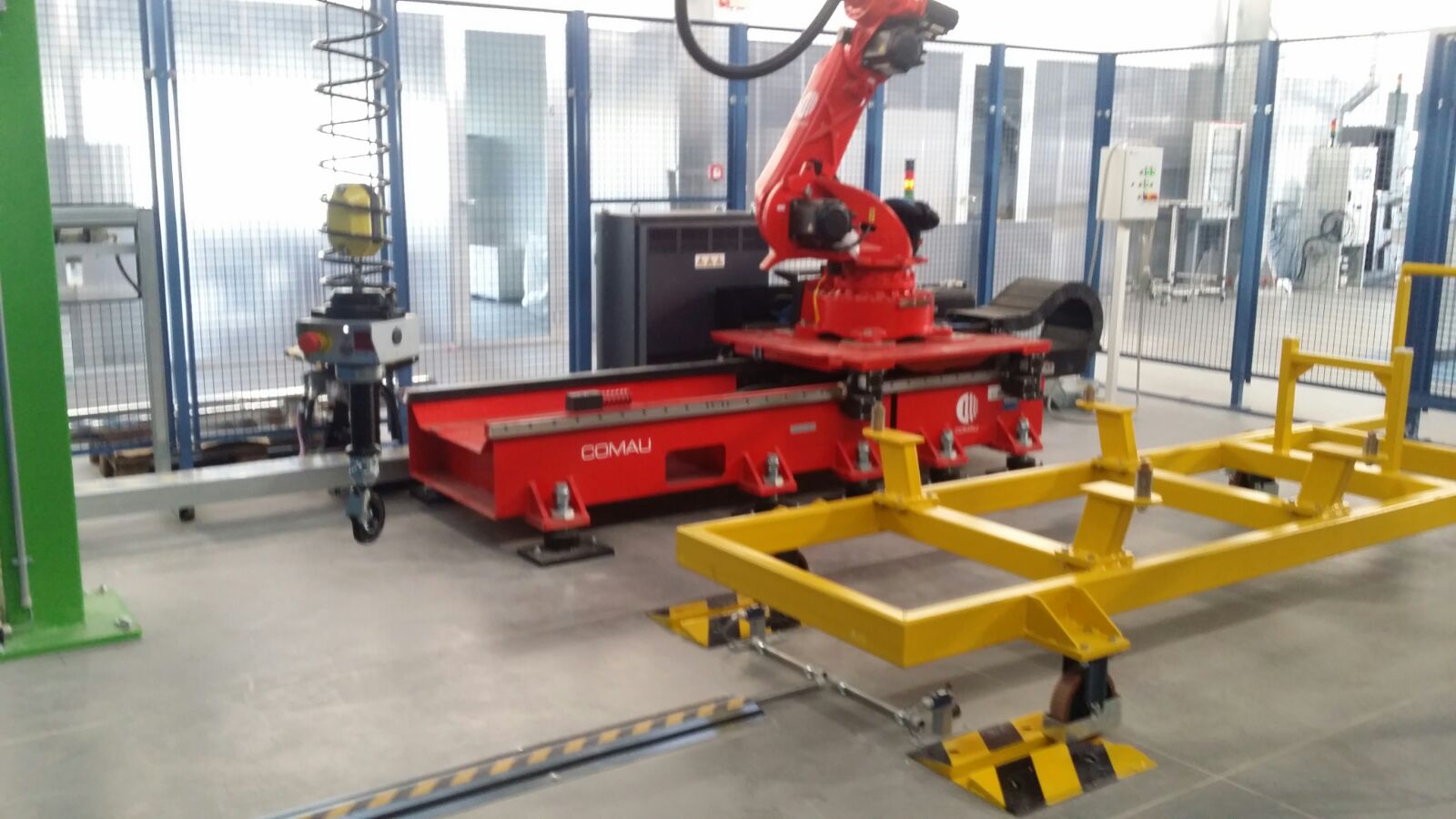 Braccio robotico industriale rosso montato su una base mobile Comau, con struttura di supporto gialla per movimentazione pezzi.