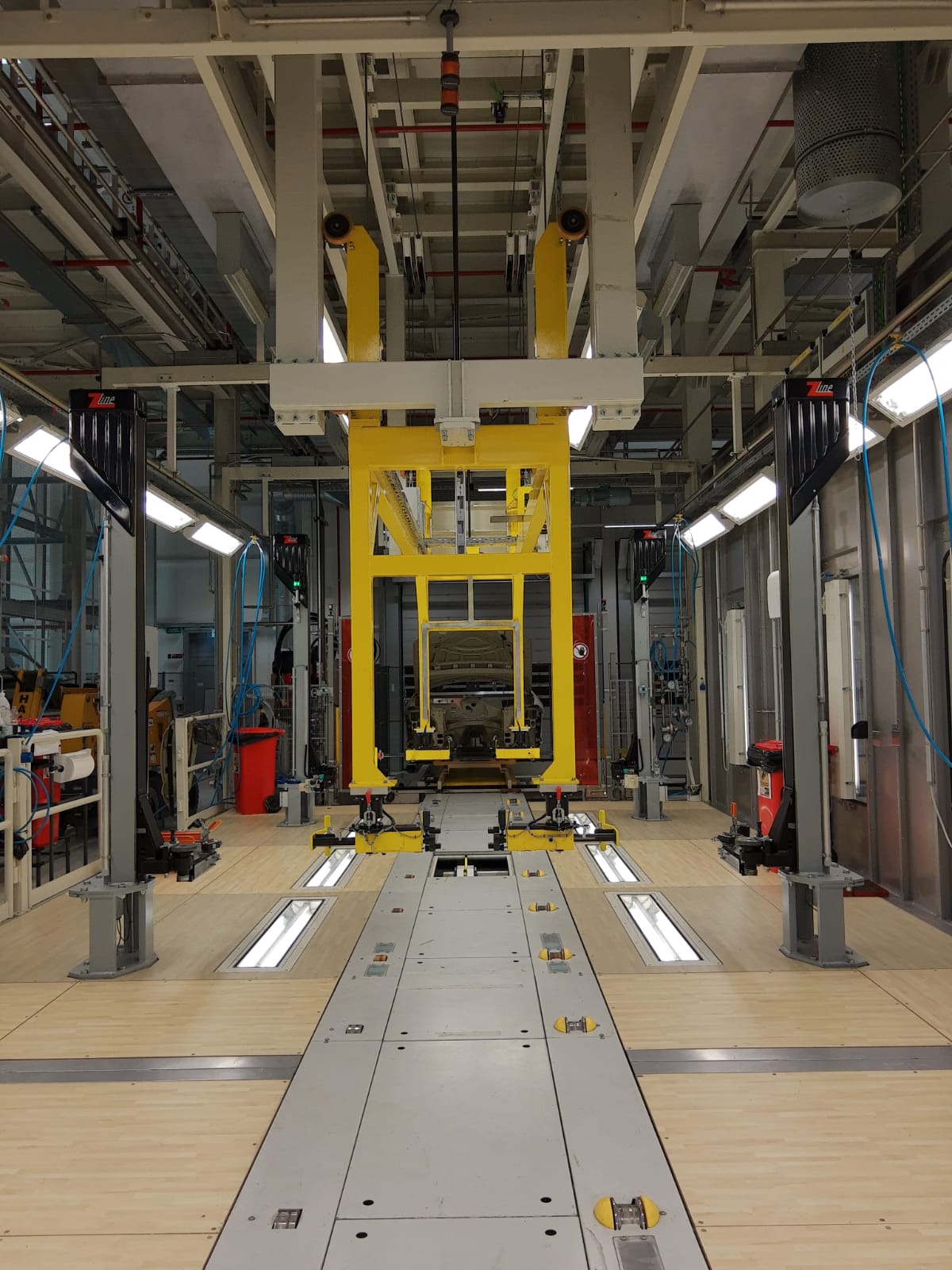 Linea di produzione con attrezzatura di movimentazione gialla per il sollevamento auto, vista centrale.