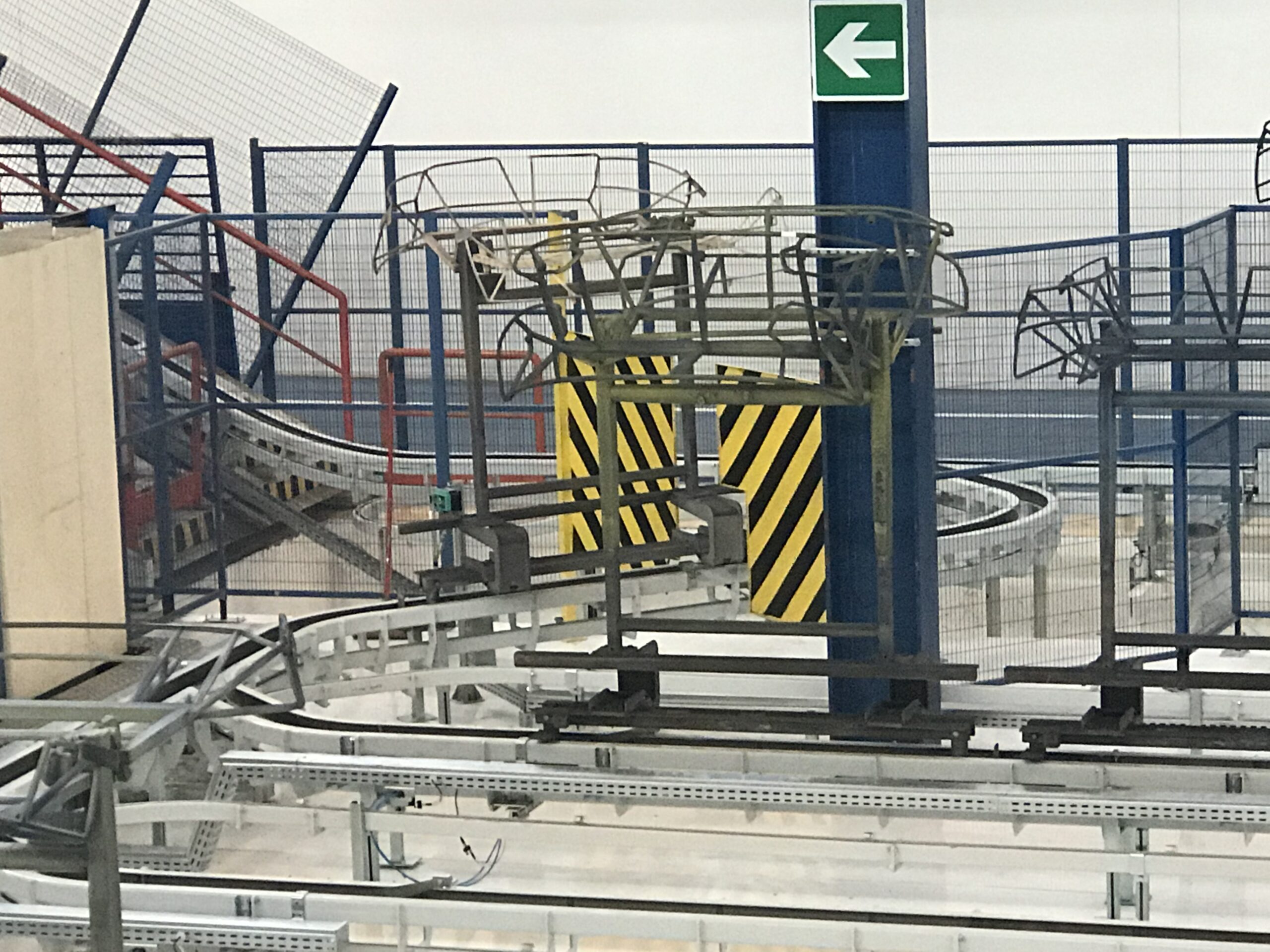 Linea di trasporto industriale con binari metallici curvi e strutture di supporto.