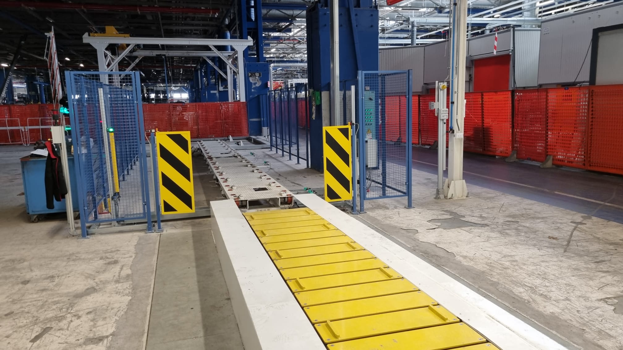 Stazione di movimentazione automatica con rulliere e sistemi di sicurezza laterali per trasporto e posizionamento carichi.