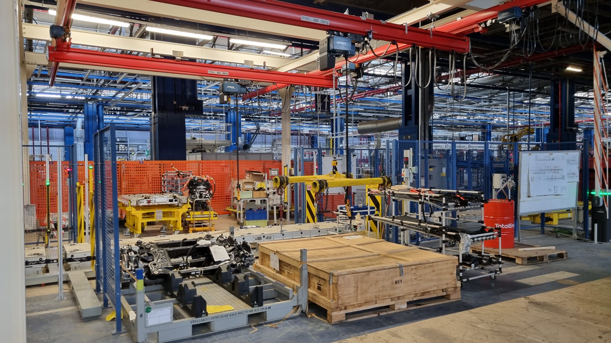 Linea di assemblaggio con strutture modulari, gru a bandiera e sistemi di movimentazione automatizzati per componenti meccanici.